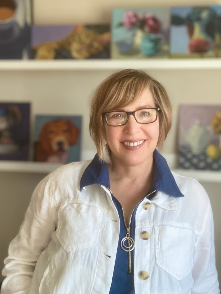 Christine McLeod, artist, in her studio with paintings in the background.